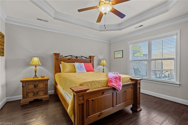 bedroom with ceiling fan, ornamental molding, dark wood-type flooring, and a tray ceiling