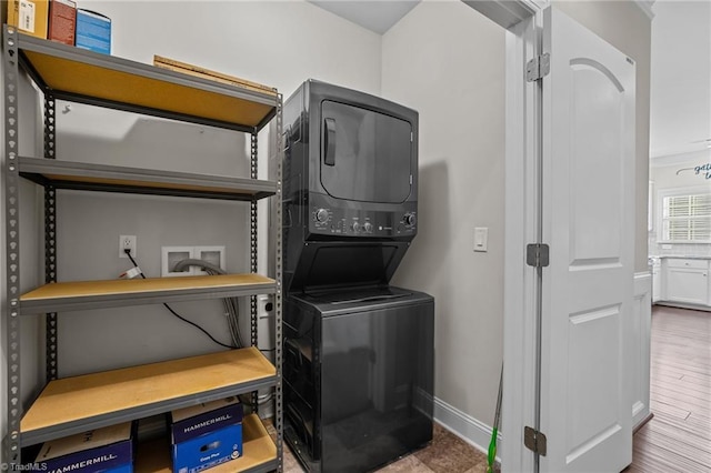 laundry area featuring stacked washing maching and dryer and hardwood / wood-style flooring