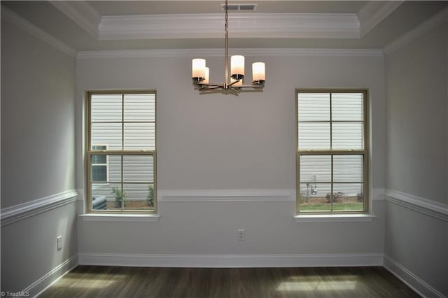 empty room with a tray ceiling, crown molding, dark wood-type flooring, and an inviting chandelier