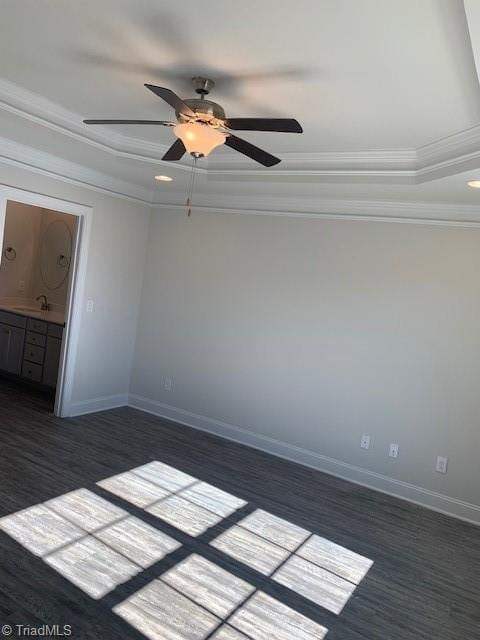 unfurnished room with dark hardwood / wood-style flooring, sink, ornamental molding, ceiling fan, and a tray ceiling