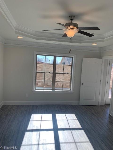 empty room featuring crown molding, dark hardwood / wood-style flooring, and a tray ceiling