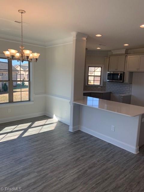 kitchen with dark hardwood / wood-style flooring, backsplash, hanging light fixtures, kitchen peninsula, and crown molding