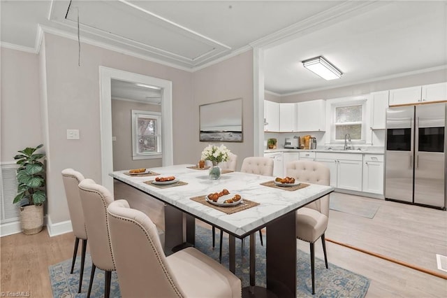 dining area featuring sink, light hardwood / wood-style floors, and crown molding