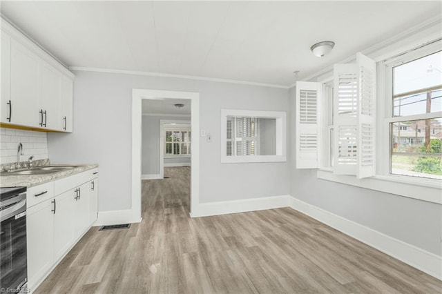 1414 E 3rd St, Winston-Salem, NC 27101 - kitchen with light wood finished floors, crown molding, backsplash, white cabinetry, and range