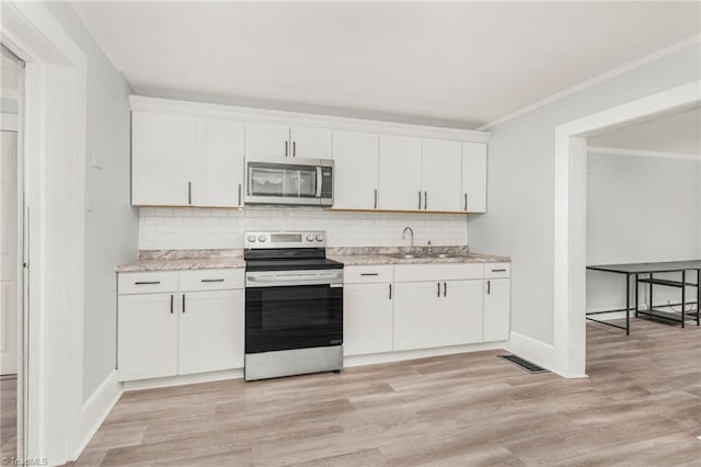 1414 E 3rd St, Winston-Salem, NC 27101 - kitchen with stainless steel appliances, white cabinets, decorative backsplash, crown molding, and light wood finished floors
