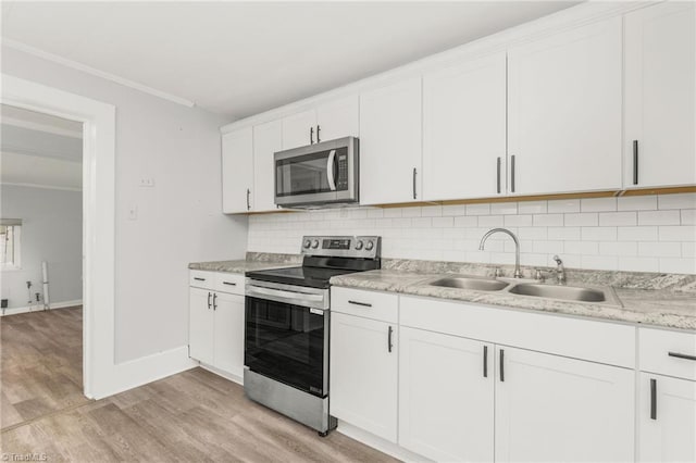 1414 E 3rd St, Winston-Salem, NC 27101 - kitchen with appliances with stainless steel finishes, ornamental molding, light wood finished floors, white cabinetry, and backsplash