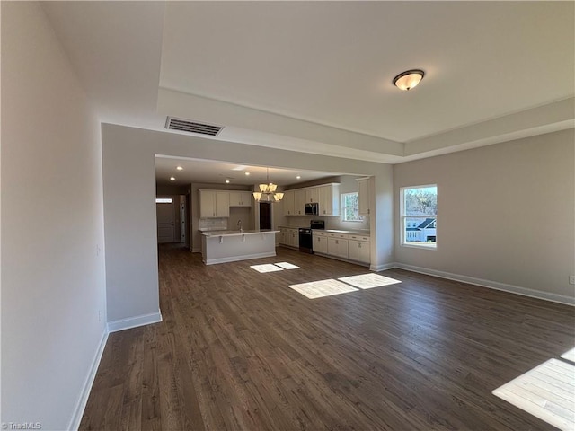 unfurnished living room featuring visible vents, baseboards, dark wood-type flooring, and a chandelier