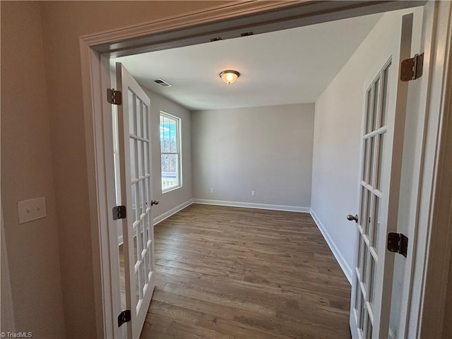 empty room featuring visible vents, baseboards, dark wood-style floors, and french doors