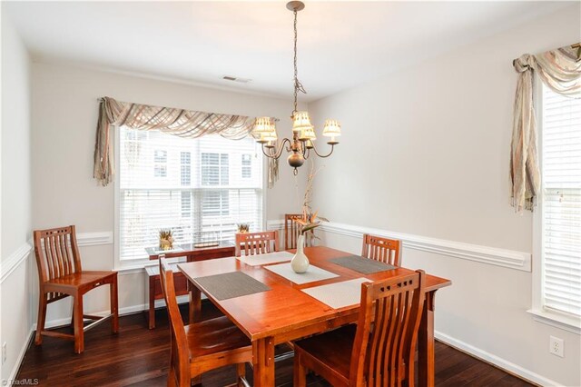 dining room featuring an inviting chandelier, dark wood-type flooring, and a healthy amount of sunlight