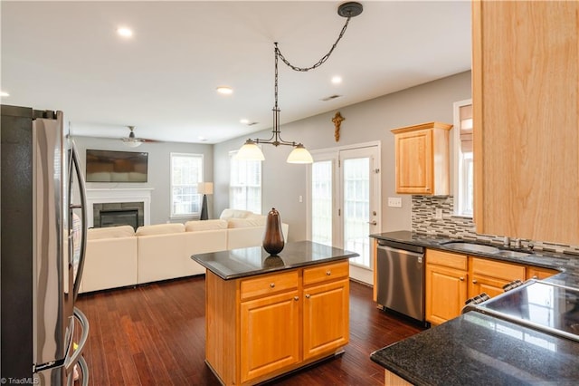 kitchen featuring backsplash, dark hardwood / wood-style flooring, stainless steel appliances, a center island, and a healthy amount of sunlight