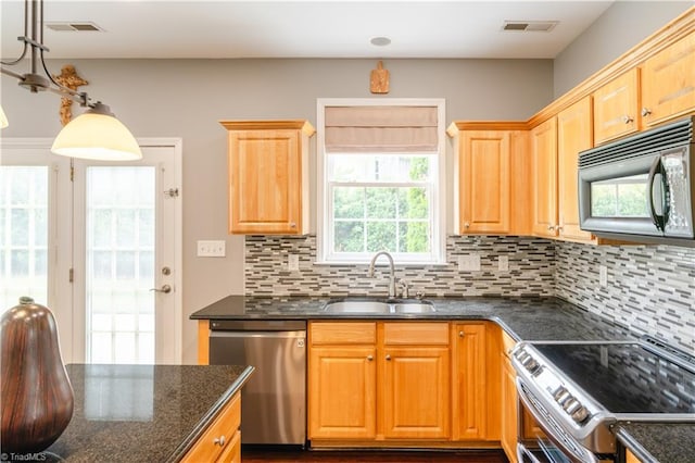 kitchen featuring sink, decorative light fixtures, backsplash, appliances with stainless steel finishes, and dark stone counters