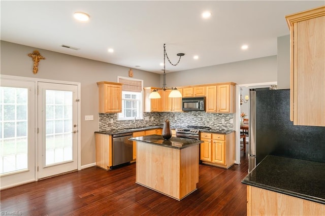 kitchen with appliances with stainless steel finishes, hanging light fixtures, a kitchen island, and dark hardwood / wood-style floors