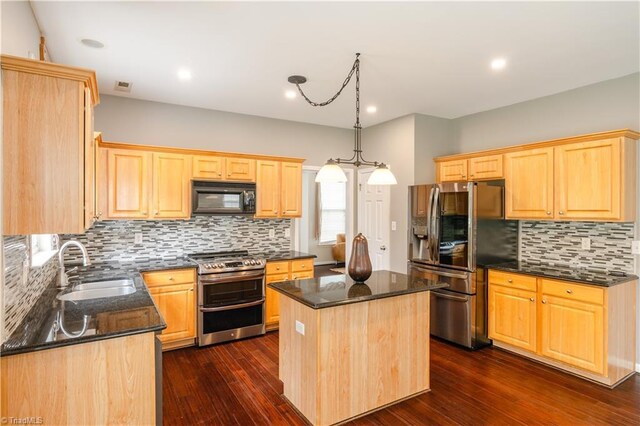 kitchen featuring a center island, dark hardwood / wood-style floors, sink, appliances with stainless steel finishes, and dark stone countertops