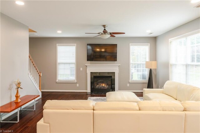 living room featuring ceiling fan, a fireplace, and dark hardwood / wood-style flooring