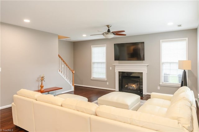 living room featuring ceiling fan, a fireplace, and dark hardwood / wood-style flooring