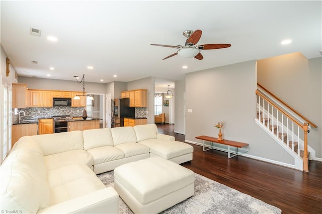 living room featuring sink, ceiling fan with notable chandelier, and dark wood-type flooring