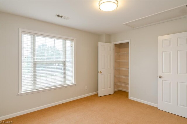 unfurnished bedroom with light carpet and a closet