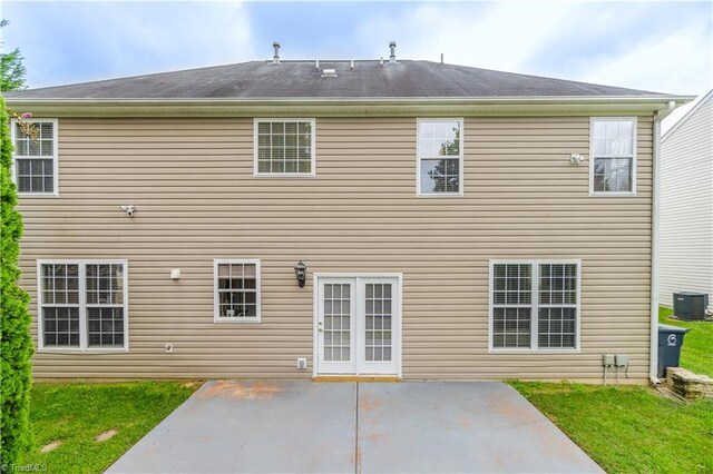 rear view of property featuring a yard, central AC unit, and a patio area