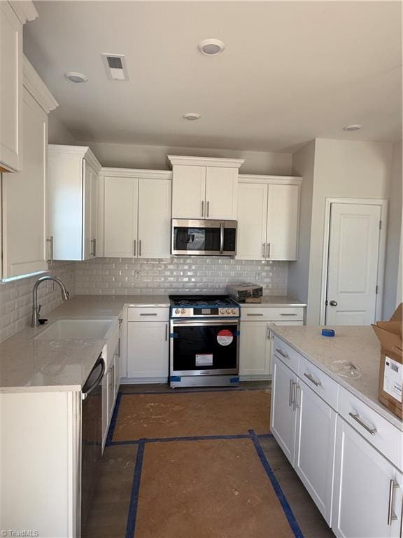 kitchen with light stone counters, sink, stainless steel appliances, and white cabinets