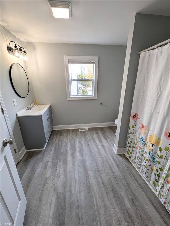 bathroom with visible vents, wood finished floors, vanity, and baseboards