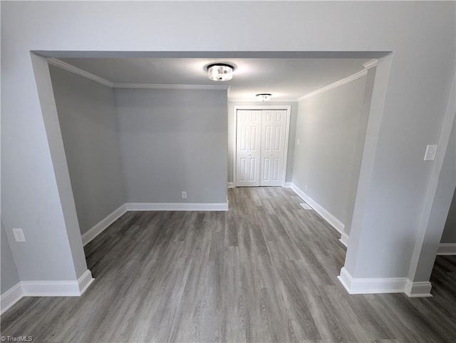 unfurnished room with baseboards, wood finished floors, and crown molding