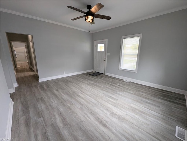 interior space featuring baseboards, visible vents, a ceiling fan, wood finished floors, and crown molding