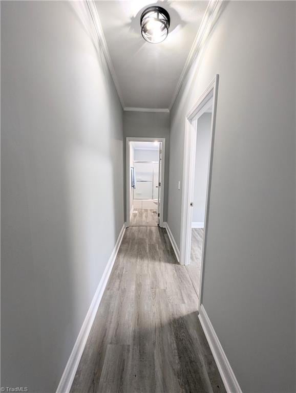 corridor with crown molding, baseboards, and wood finished floors