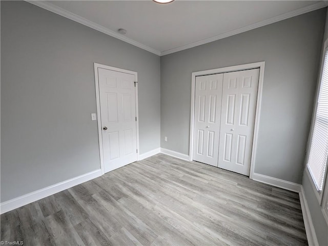 unfurnished bedroom featuring a closet, crown molding, baseboards, and wood finished floors