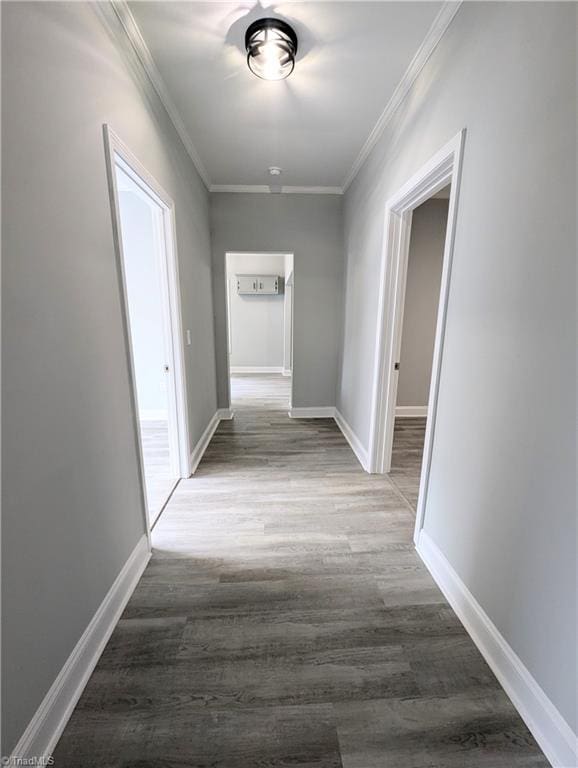 hall featuring ornamental molding, baseboards, and wood finished floors