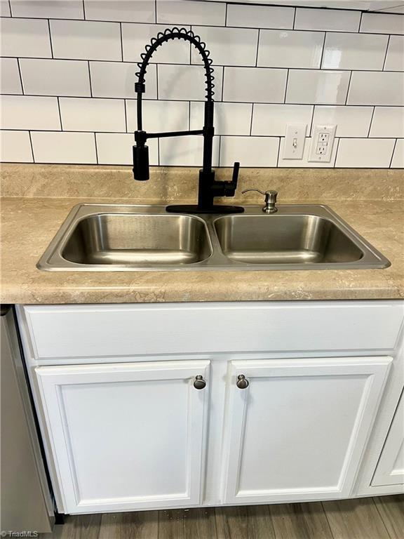 interior details featuring tasteful backsplash, sink, dishwashing machine, and white cabinets