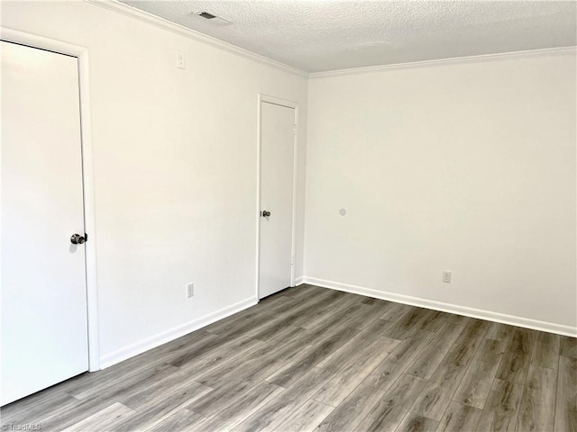 empty room with ornamental molding, hardwood / wood-style floors, and a textured ceiling