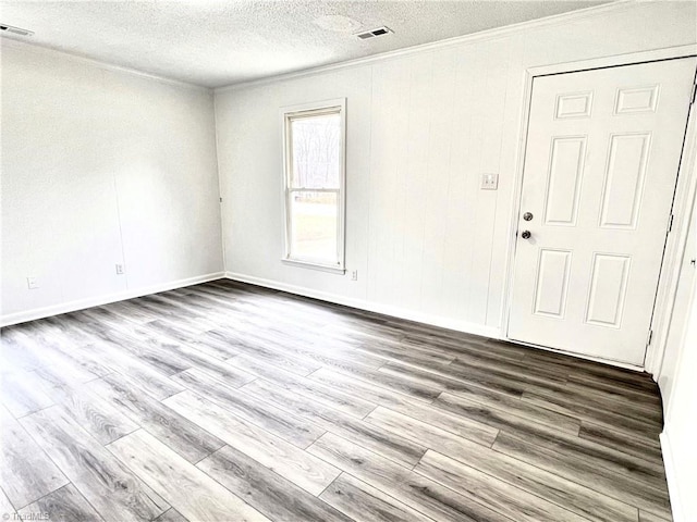 empty room with crown molding, a textured ceiling, and light hardwood / wood-style flooring