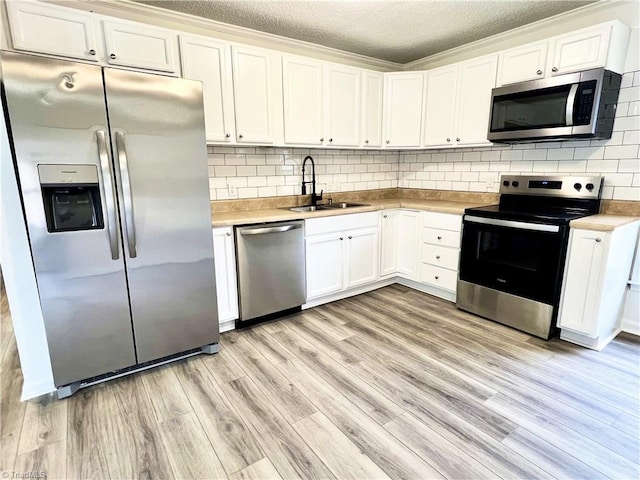 kitchen featuring sink, backsplash, white cabinets, stainless steel appliances, and light wood-type flooring