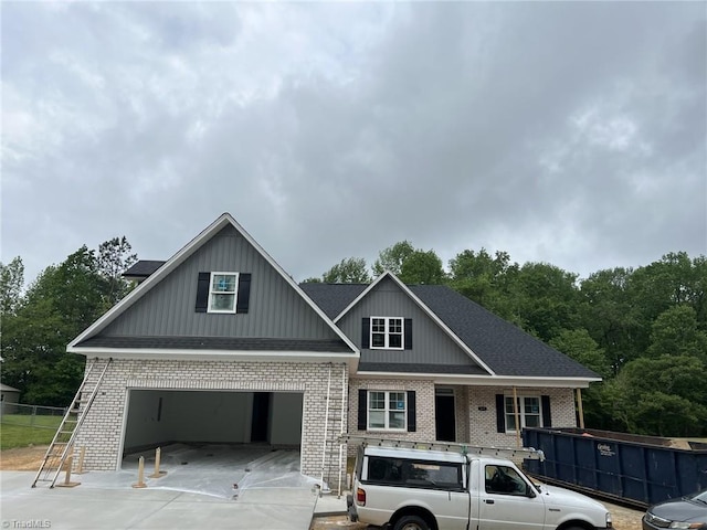 craftsman-style house featuring a garage, brick siding, fence, and concrete driveway