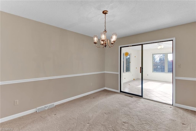 spare room with carpet, a notable chandelier, and a textured ceiling