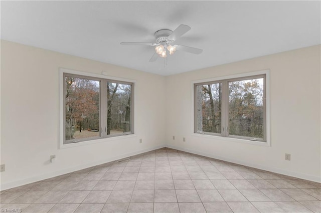 tiled spare room featuring ceiling fan and a healthy amount of sunlight