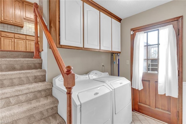 clothes washing area featuring washer and clothes dryer, cabinets, and a textured ceiling