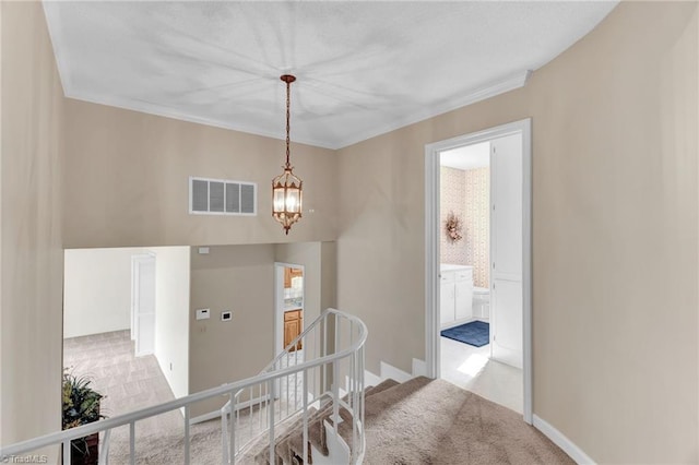 hall with a notable chandelier, light colored carpet, and ornamental molding