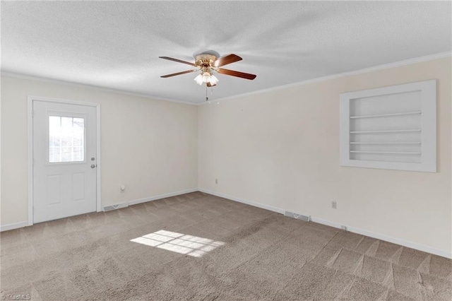 carpeted empty room with ceiling fan, built in features, a textured ceiling, and ornamental molding