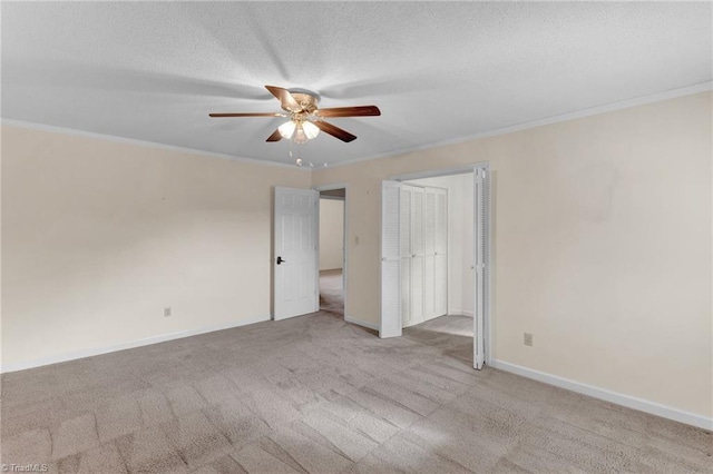 carpeted spare room with ceiling fan, a textured ceiling, and ornamental molding