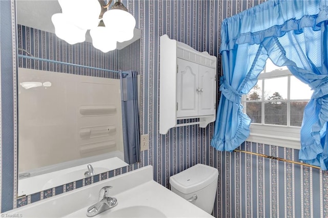 bathroom featuring a notable chandelier, toilet, walk in shower, and vanity