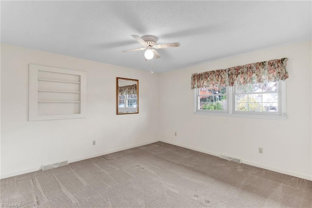 spare room featuring ceiling fan, carpet floors, and built in shelves