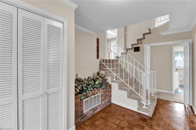 foyer with ornamental molding, a textured ceiling, and dark parquet floors