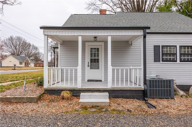 bungalow-style house featuring central air condition unit, a porch, and a shingled roof