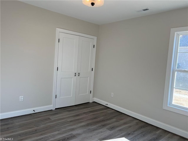 unfurnished bedroom with dark hardwood / wood-style flooring and a closet