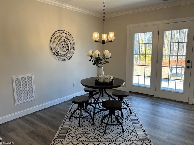 dining area featuring dark hardwood / wood-style flooring, ornamental molding, and a chandelier