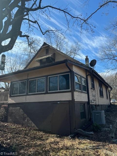 view of side of home featuring central air condition unit and a chimney