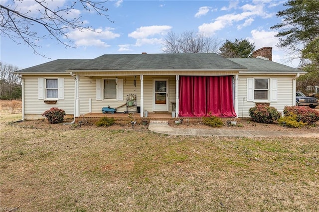 ranch-style house with covered porch, a chimney, and a front lawn