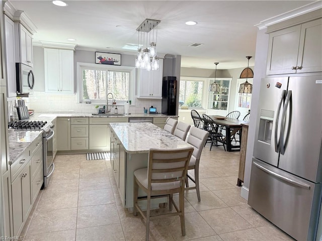 kitchen featuring decorative light fixtures, appliances with stainless steel finishes, a sink, and a center island