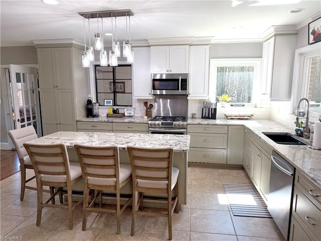 kitchen with stainless steel appliances, a sink, a kitchen island, and a kitchen bar